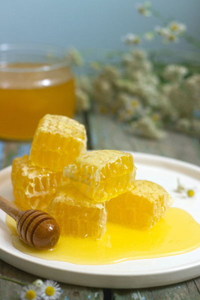 蜂蜜在一个玻璃罐子和蜂蜜在蜂巢在一个古老的木制背景