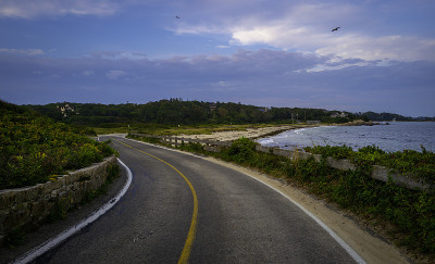 弯曲的双车道海岸公路和戏剧性的云景沿着法尔茅斯高地海滩在科德角