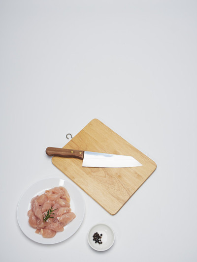 将一小块生鸡肉放在一个白色的盘子里，配上配料。食品菜单设计。