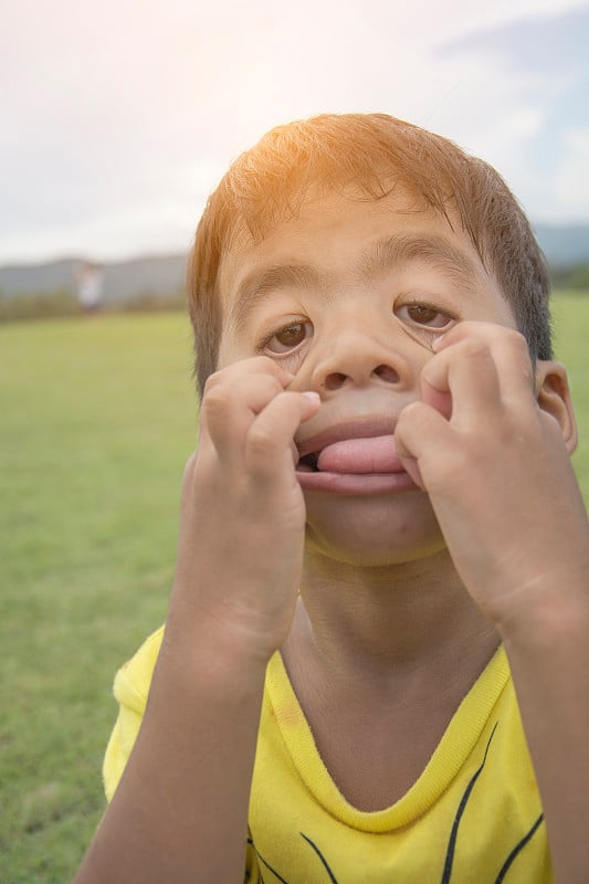 一个五岁的小男孩像鬼一样想吓唬妈妈，他把舌头放在舌头上，伸出舌头，做鬼脸