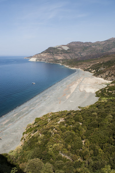 科西嘉岛:从空中俯瞰普拉格·德·诺扎(Plage de Nonza)，悬崖底部长长的黑色海滩上矗立着