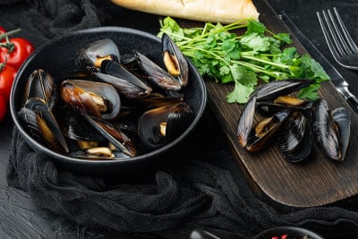 煮贻贝壳与香料和香草，碗，在黑色背景