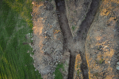 地热能收集坑或地沟的航空无人机视图。为房屋的热交换器挖掘沟渠或洞。在外面的田野上。