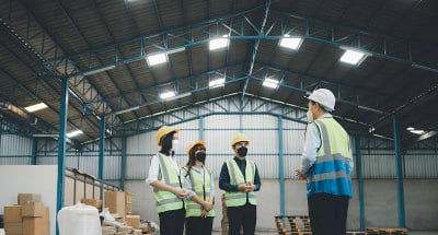 一组戴着医用口罩的工作人员在工厂召开安全会议，树立工作安全卫生观念