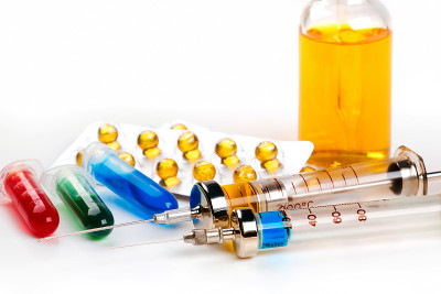 带药物的注射器、泡罩包装、小瓶和白色背景上带彩色液体的瓶子