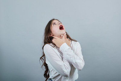 穿白衬衫的女人双手扼住脖子，哽咽着，抬起头