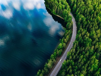 芬兰绿色森林和蓝色湖泊之间的公路鸟瞰图