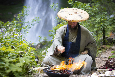 奥地利大瀑布前，一名蓄着胡须、穿着日式长袍的欧洲男子正在举行火葬仪式