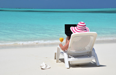 在热带海滩上拿着笔记本电脑的女孩。Exuma,巴哈马群岛