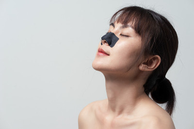 美丽的亚洲女模特用活性炭面膜深层清洁鼻子毛孔，清新洁净的肌肤。