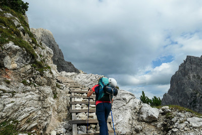 Oberbachernspitze -女人背着大背包和棍子，走在意大利高白云石的木楼梯上。-一个女人