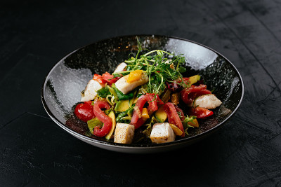 黑色背景上的虾仁、蔬菜和蟹肉沙拉