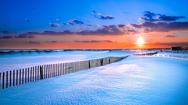 冬季海滩景色与雪在日落