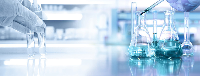 拥有医用化学实验室旗帜背景的试管和烧瓶科学家的手