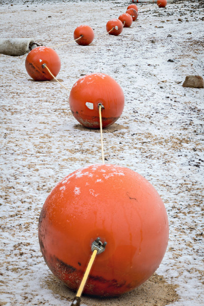 橙色的浮标球在岸边，地上覆盖着冬天的雪