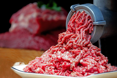 绞碎的肉从绞肉机里出来。健康的自制肉糜。黑暗的背景。水平查看照片。copyspace。