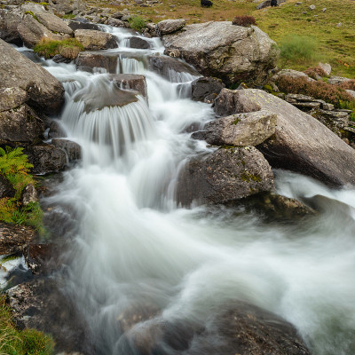 秋天，在斯诺登尼亚的Llyn Ogwen和Llyn Idwal附近，一条河流顺着山脉流下的穆迪景观图