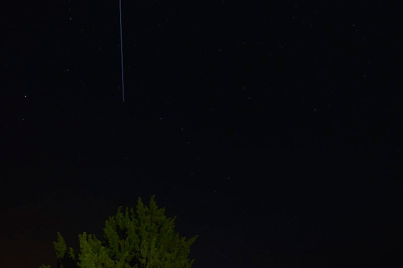 照片上的星星在一个晴朗的夏天的云与不明飞行物通过仙后座汽车。夜景摄影，风景，占星术，科学。