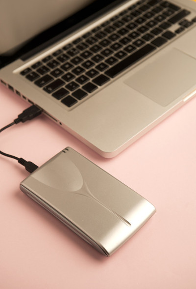 铝制外置硬盘带数据线(usb)，笔记本电脑局部视图，粉色桌子。