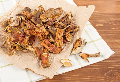 干蘑菇撒在木桌上皱巴巴的纸上。有机、环保食品