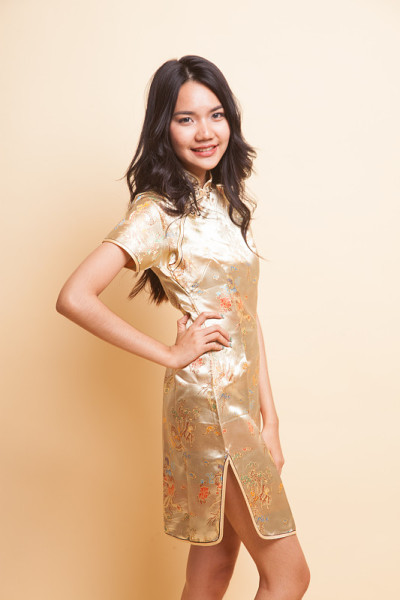 身穿金色中国旗袍的亚洲女孩的肖像