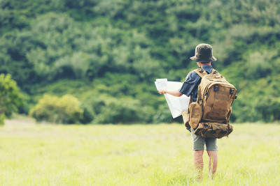 亚洲男孩背包检查地图在丛林森林，旅行冒险和旅游的目的地和休闲教育和放松在自然公园。旅游度假的概念