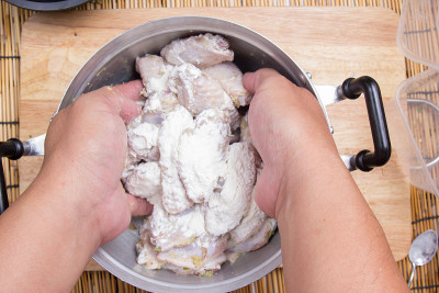 厨师将面粉加入鸡翅中烹饪