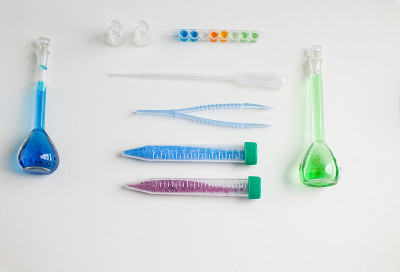 一套学校用品，生物或化学课上的光背景:玻璃烧瓶，镊子，吸管，塑料管铜和钴盐。理念:回到学校。Flat