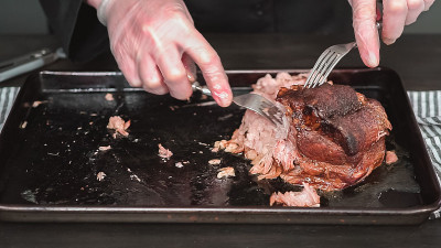 用两把叉子切猪肉烤肩肉。