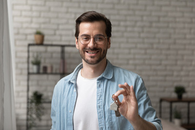 友善的男子经纪人摆出出售公寓钥匙的姿势