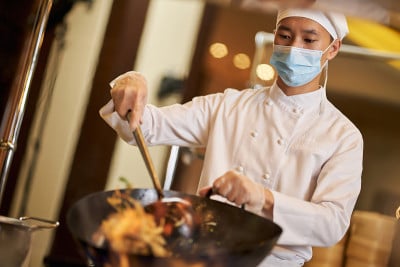熟练的男厨师戴着防护面具工作