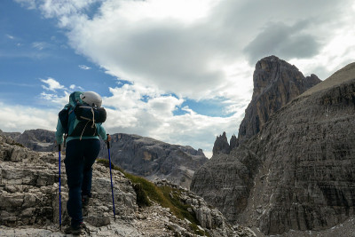 Oberbachernspitze -女人与大背包和手杖徒步旅行在高意大利白云石。
