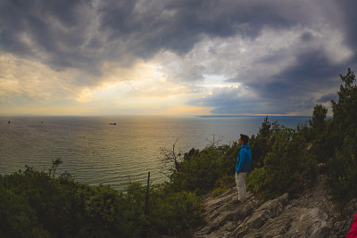 年轻人在日落时眺望大海，欣赏着美景