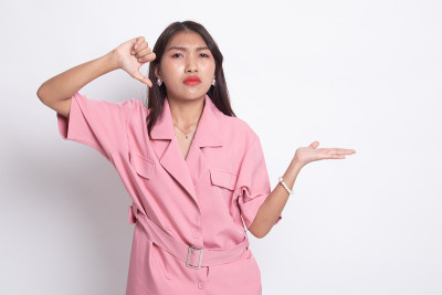 年轻的亚洲妇女显示手掌和拇指向下。