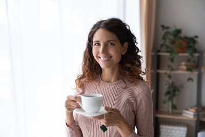 女子站在室内，端着一杯刚泡好的茶