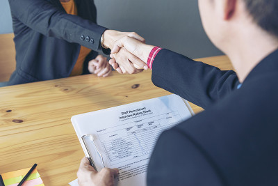 商务面试由人力资源人力资源官面试，谈话新员工在办公室微笑握手。HR经理面试，面对面查看简历。面试的概