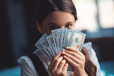 Girl holding dollars and closing her face