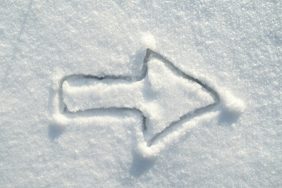 在一个阳光明媚的日子里，雪地上画着箭头符号。向右移动。副本的空间。前视图。
