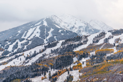 阿斯彭，美国科罗拉多州的酪乳滑雪山坡山坡在岩石山脉的观点暴风雨的云和山顶与黄色树叶上的雪秋天的树木