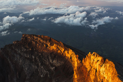 在巴厘岛日出峰顶的阿贡火山边缘。云朵之上，五彩缤纷的风景。初升太阳的第一缕阳光是橙色的。阿贡火山顶部