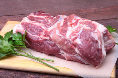 生猪颈剁肉和欧芹叶在石头背景上。准备做饭。