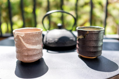 铸铁茶壶在桌子上的花园围墙外的两个杯子和日本美诺茶杯在早上近距离