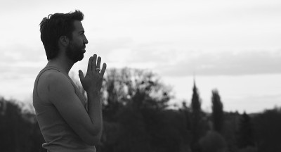 一名男子双手站立，摆出祈祷的姿势。