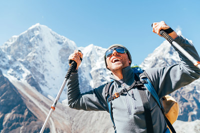 在塔波切6495米和Cholatse 6440米的山峰上微笑的徒步者的肖像，背景是徒步杆，紫外线防护