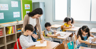 小学生在小学教室里与老师击掌。在小学学习的男生。孩子们在教室里写笔记。教育知识，成功团队理念旗帜