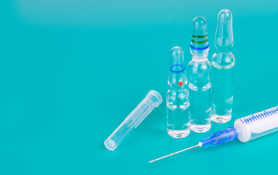 蓝色背景上用于注射的医用注射器和安瓿。副本的空间。