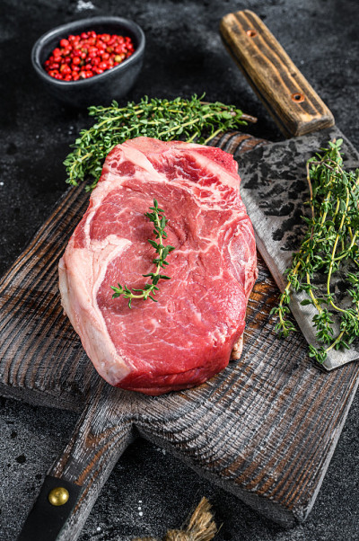 生牛肉在带骨的肉排上。黑色的地面。俯视图