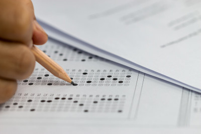 教育考试考试的概念，高中/大学学生拿着铅笔写纸答题纸坐在椅子上，在考场或教室参加考试。教育评价理念