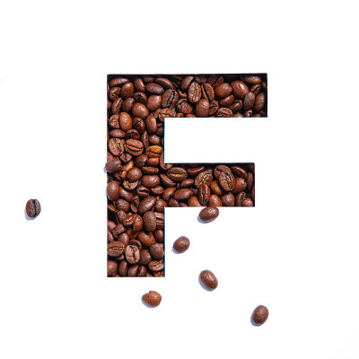 英文字母F由咖啡豆和纸切割成孤立的白色字母
