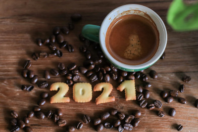 2021面包和咖啡杯放在放着咖啡豆的木桌上。2021年新年快乐，节日美食艺术概念。(关闭)